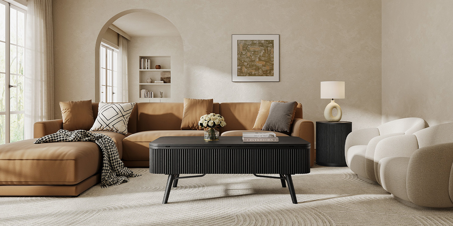A modern black fluted coffee table with mid-century styled legs centered in a living room with a camel leather sofa and white accent chairs.