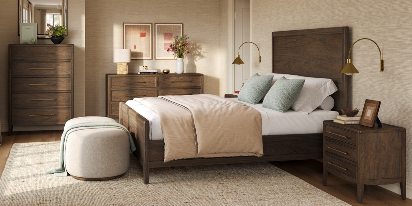 A dark wood king bed frame with matching dressers and a nightstand, styled with gold wall lamps and a fabric ottoman. A dark wood king bed frame with matching dressers and a nightstand, styled with gold wall lamps and a fabric ottoman.