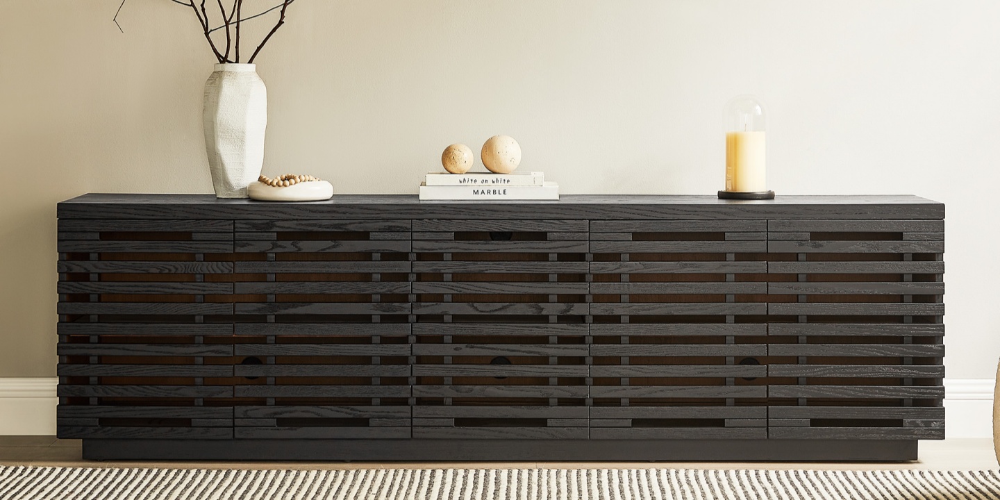 Ingrid 84-inch black oak slatted media console styled with decor, ideal as tv stands for 70 inch tv setups in a living room.