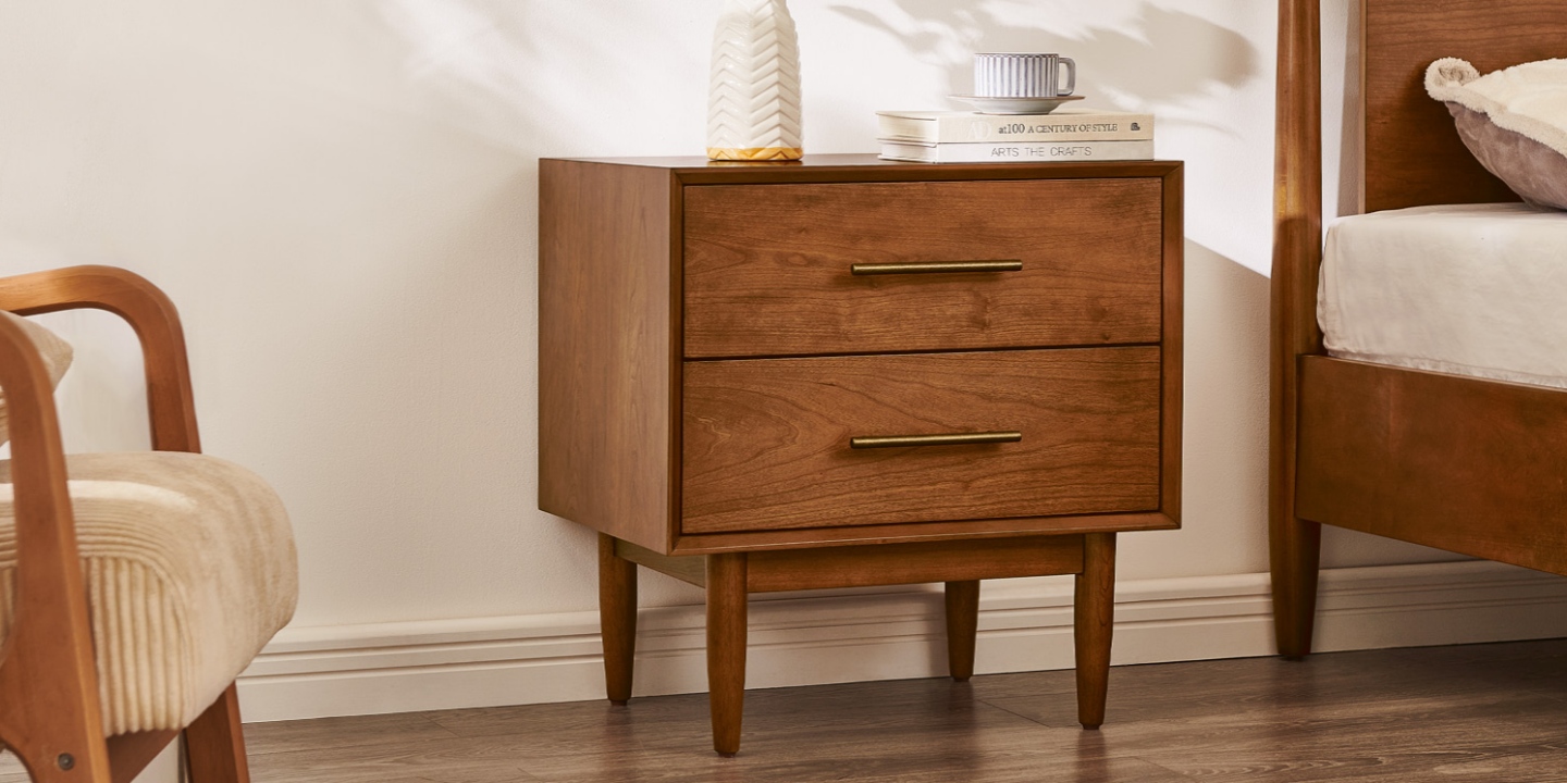 Mid-century style Kaden 23-inch nightstand featuring clean lines, tapered wooden legs, and antique bronze hardware in a bedroom. Mid-century style Kaden 23-inch nightstand featuring clean lines, tapered wooden legs, and antique bronze hardware in a bedroom.