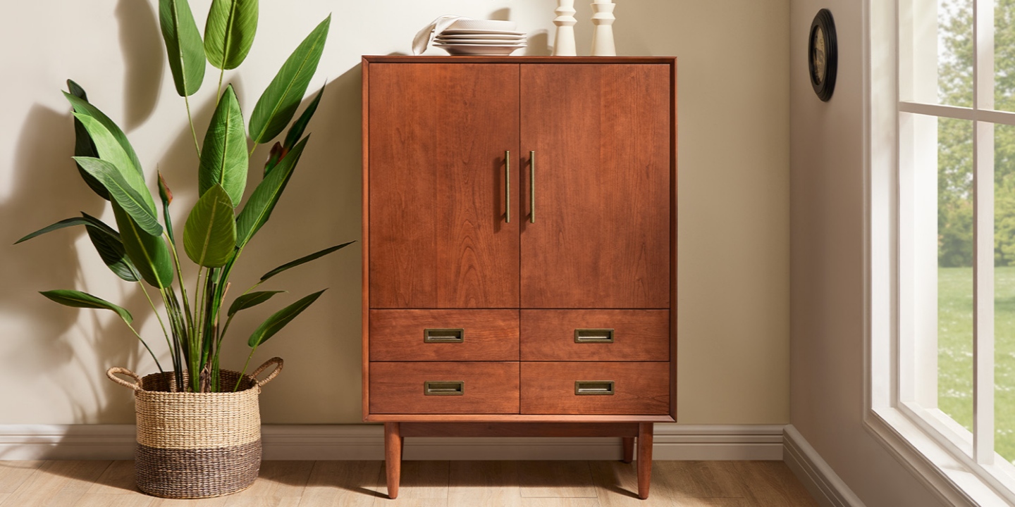 Next to a large potted plant, the Kaden mid-century bar cabinet showcases cherry veneers and antique bronze hardware. Next to a large potted plant, the Kaden mid-century bar cabinet showcases cherry veneers and antique bronze hardware.