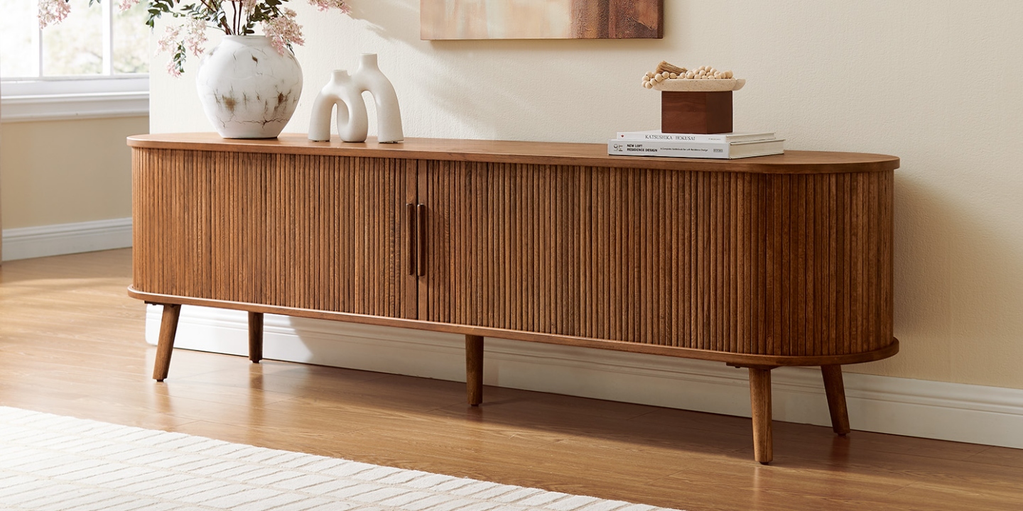 Hernest Valo 84-inch warm brown oak fluted TV stand featuring curved tambour doors and tapered legs in a bright living room.
