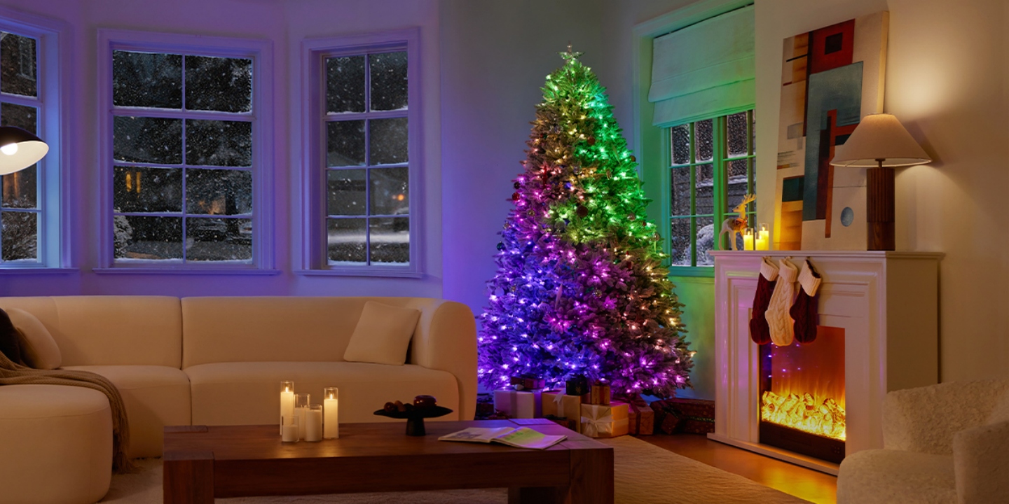 Cozy winter living room featuring the Hernest CastGlow artificial Christmas tree glowing next to a snowy window and fireplace. Cozy winter living room featuring the Hernest CastGlow artificial Christmas tree glowing next to a snowy window and fireplace.