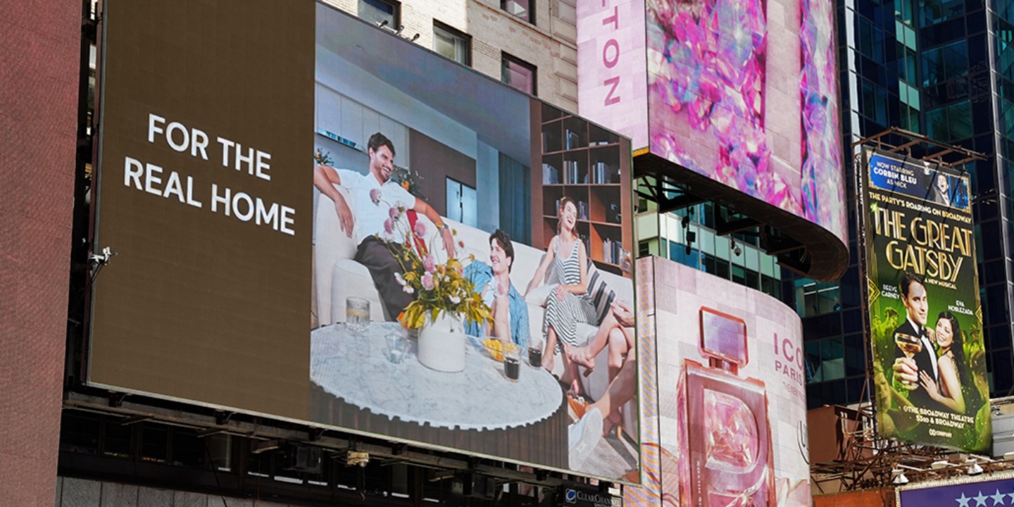 A large digital billboard in Times Square showcasing Hernest with the text For the Real Home and a warm gathering scene. A large digital billboard in Times Square showcasing Hernest with the text For the Real Home and a warm gathering scene.