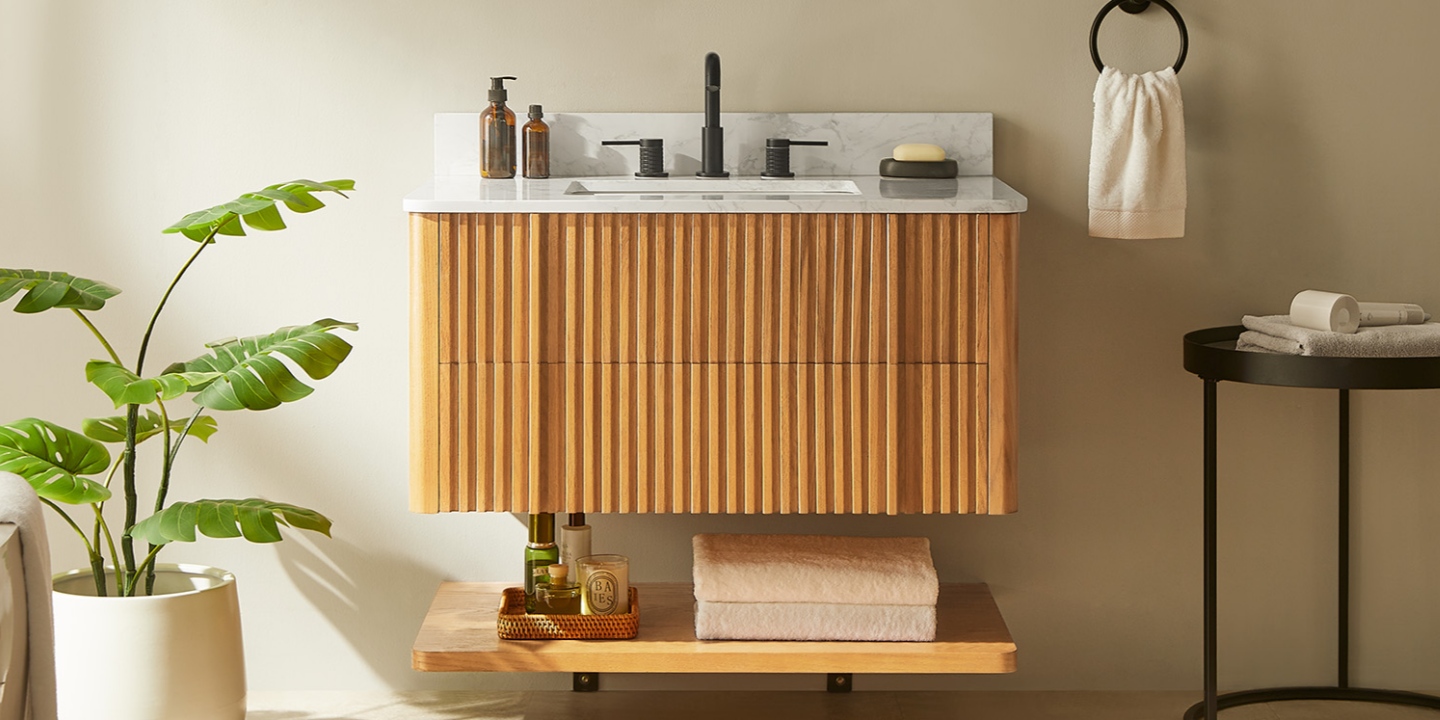 A modern, floating light wood vanity with fluted panels and a marble top, featuring a lower shelf with towels and accessories. A modern, floating light wood vanity with fluted panels and a marble top, featuring a lower shelf with towels and accessories.