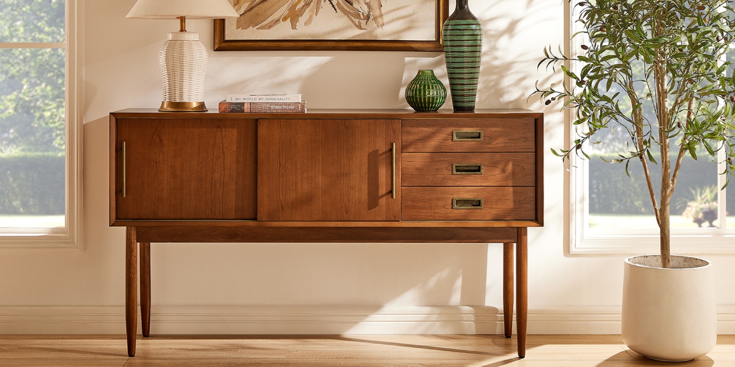 This mid-century cherry wood console table features sliding doors, golden metal handles, tapered legs, and tabletop decor. This mid-century cherry wood console table features sliding doors, golden metal handles, tapered legs, and tabletop decor.