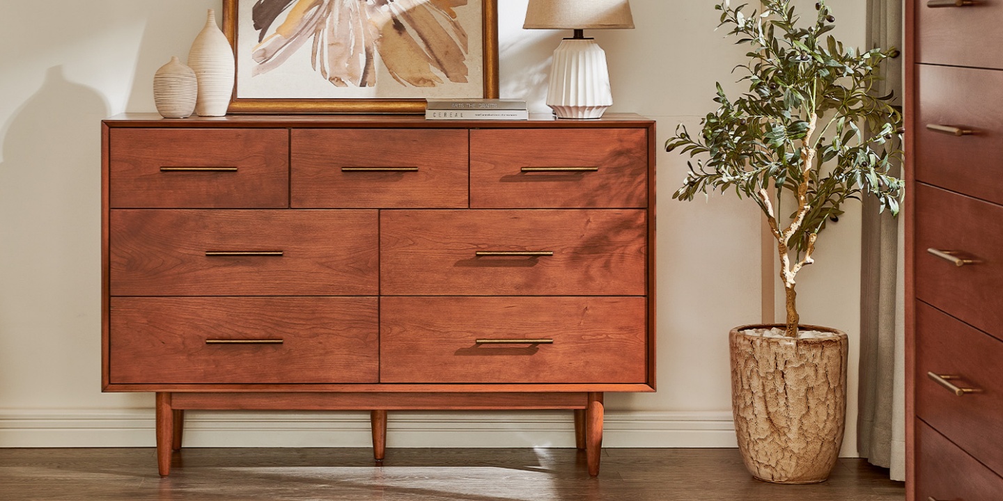 This 55-inch Kaden mid-century wood dresser features seven drawers, antique bronze hardware, and tapered wooden legs. This 55-inch Kaden mid-century wood dresser features seven drawers, antique bronze hardware, and tapered wooden legs.