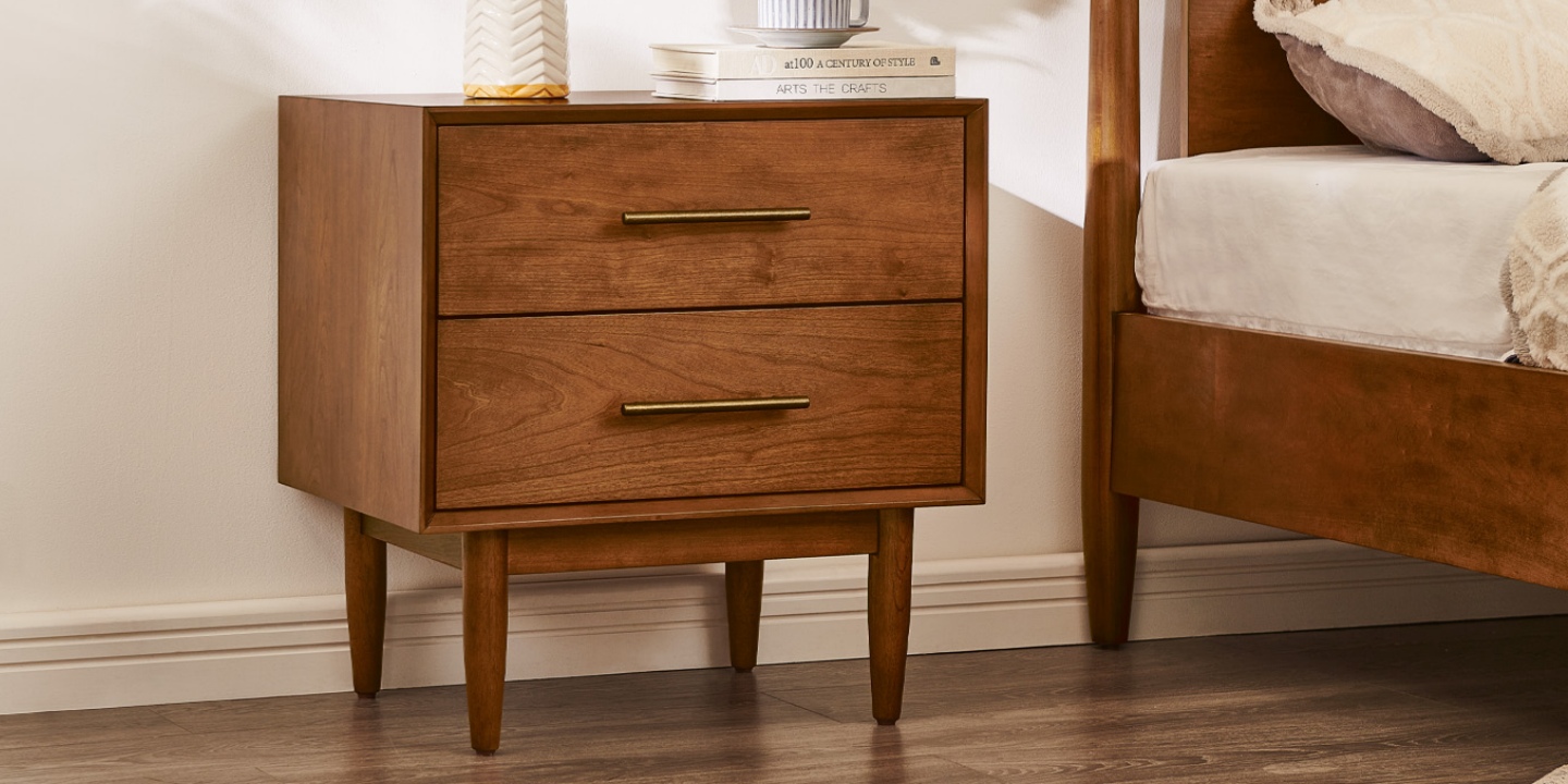 This Kaden mid-century nightstand in a warm cherry finish features two drawers, antique bronze hardware, and tapered legs. This Kaden mid-century nightstand in a warm cherry finish features two drawers, antique bronze hardware, and tapered legs.