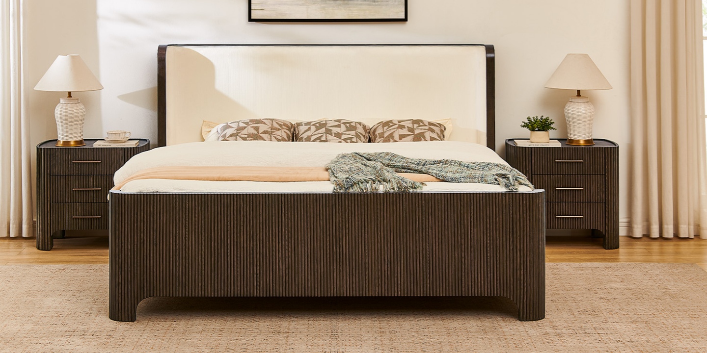 A stylish king bed frame with dark fluted panels and an upholstered headboard, flanked by matching bedside tables. A stylish king bed frame with dark fluted panels and an upholstered headboard, flanked by matching bedside tables.