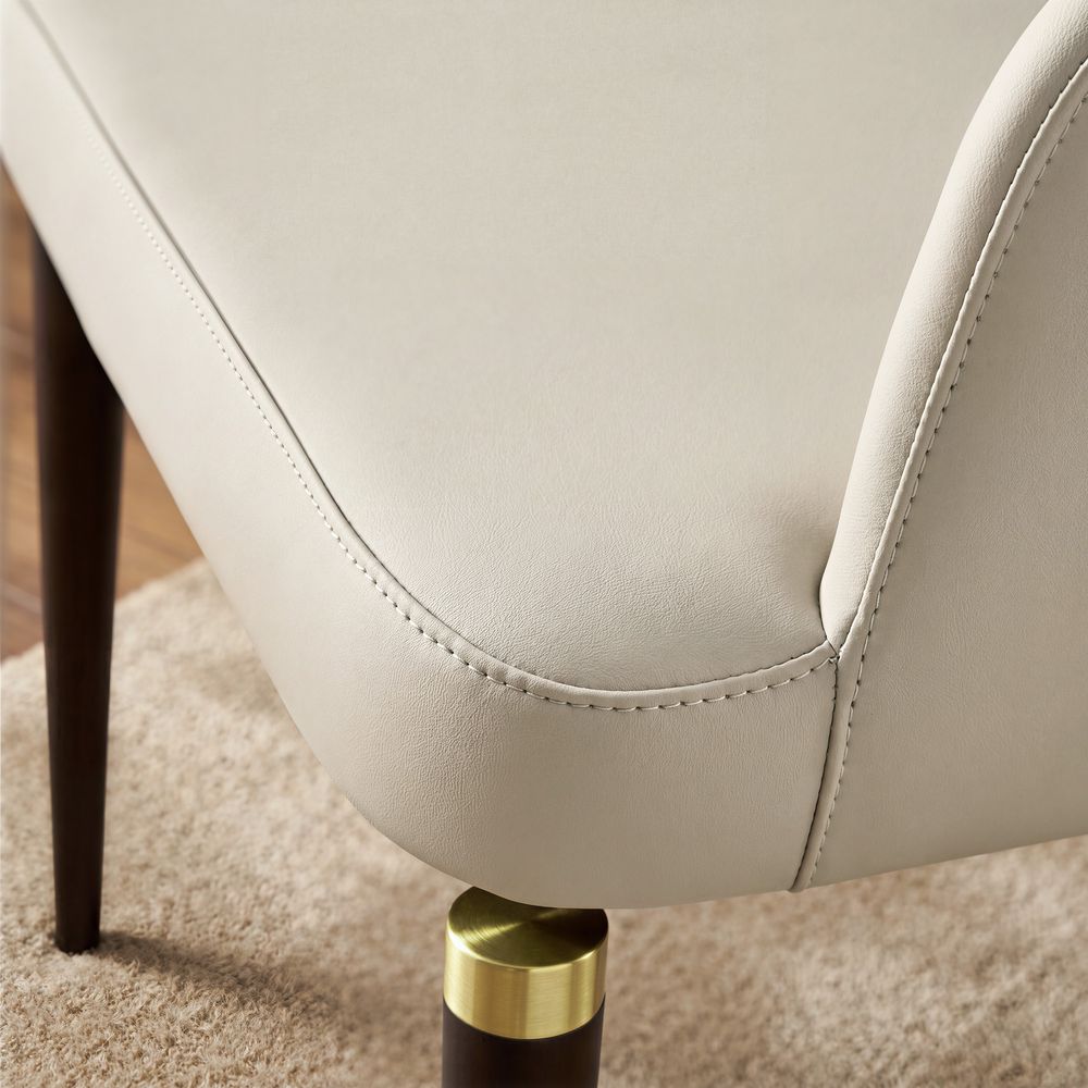 Close-up of the Hernest Liliana Armrest Leather Dining Chair, highlighting the curved armrest, beige PU leather seat, and golden leg accents.
