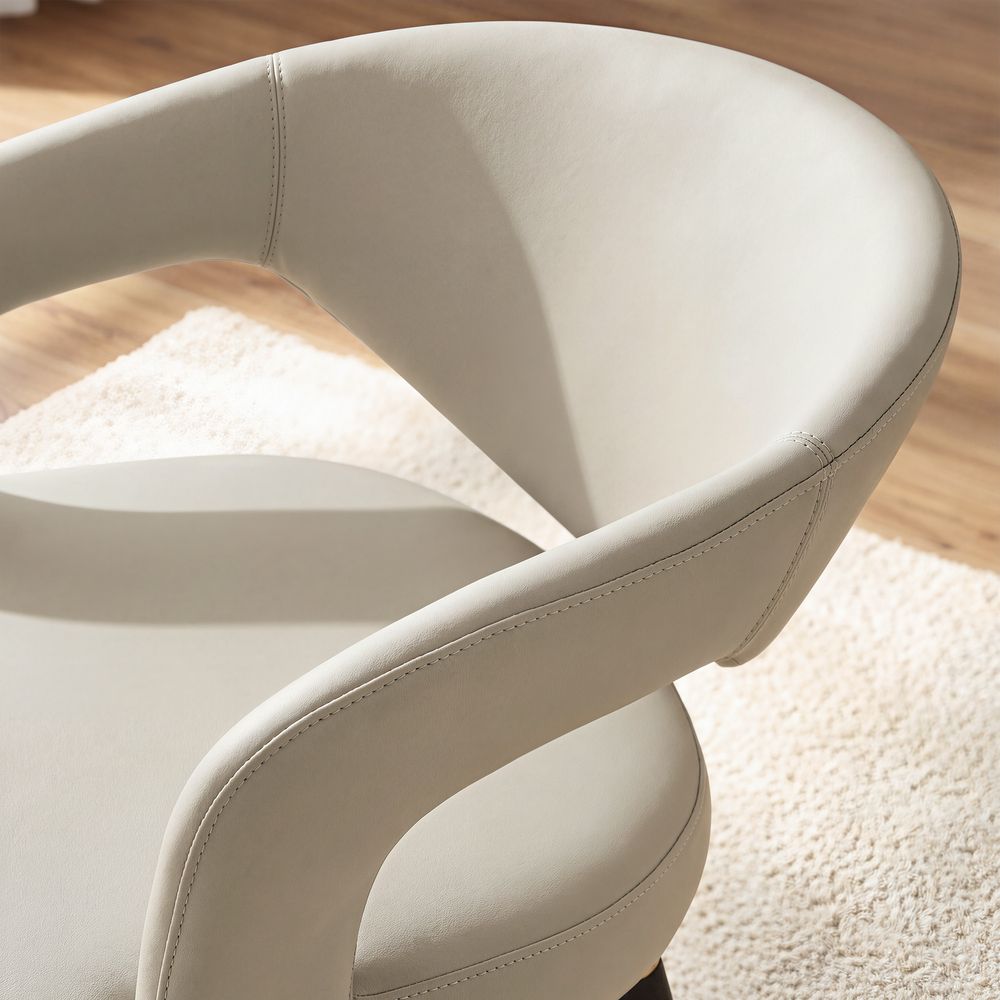 Close-up of the beige Hernest Liliana Armrest Leather Dining Chair, highlighting the curved, stitched backrest and integrated arm design.