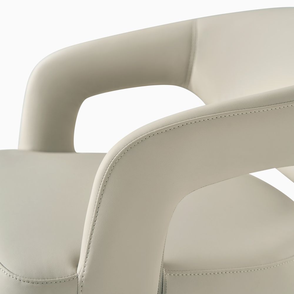 Close-up of the beige Hernest Liliana Armrest Leather Dining Chair, highlighting the curved, stitched backrest and integrated arm design.