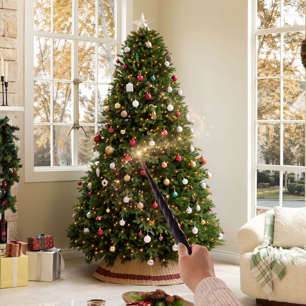 CastGlow 7.5 ft pre-lit artificial Christmas tree decorated in a living room with a magic wand controlling lights.